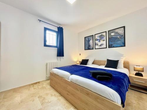 une chambre avec un grand lit avec une couverture bleue dans l'établissement Le Jasmin 2 - Chic, Clim, Terrasse, Neuf, 3 lits, 4 personnes, à Fos-sur-Mer