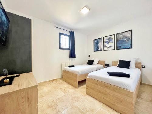 - une chambre avec 2 lits et une télévision murale dans l'établissement Le Jasmin 2 - Chic, Clim, Terrasse, Neuf, 3 lits, 4 personnes, à Fos-sur-Mer