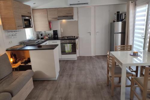 une cuisine avec des armoires blanches, une table et un canapé dans l'établissement Comfortable 2-bedroom mobile home, à Canet