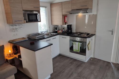 une cuisine avec des armoires blanches et un four à plaques de cuisson dans l'établissement Comfortable 2-bedroom mobile home, à Canet