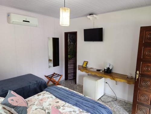 a bedroom with a bed and a tv on the wall at Pousada e Restaurante Dona Siroba in Morretes