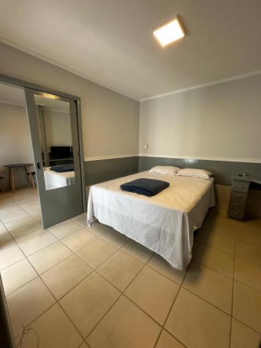 a bedroom with a bed and a mirror at Flat Crystal Place in Goiânia