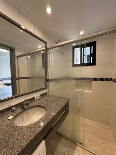 a bathroom with a sink and a glass shower at Flat Crystal Place in Goiânia