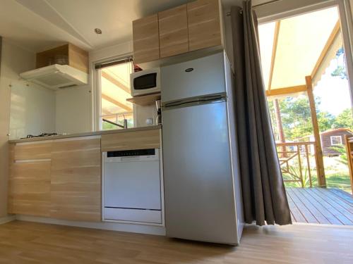 - un réfrigérateur blanc dans une cuisine avec fenêtre dans l'établissement Mobile home in 5-star camping, à Montalivet-les-Bains