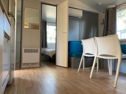 - une chambre avec deux chaises blanches et un lit dans l'établissement Mobile home in 5-star camping, à Montalivet-les-Bains