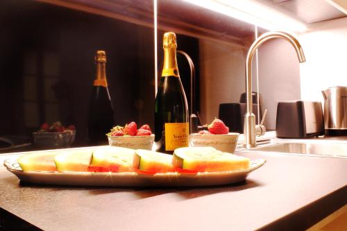un plato de fruta en un mostrador con botellas de vino en Milford Suites Budapest, en Budapest