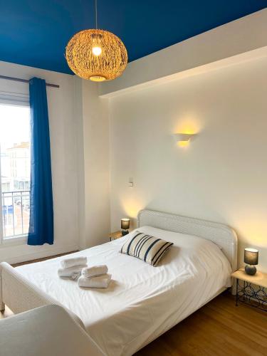 une chambre avec un lit blanc avec des serviettes dessus dans l'établissement L'Ecume, à Royan