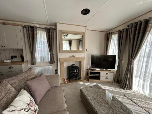 a living room with a couch and a television at Lodge 2 The Wee Hut Aviemore in Aviemore