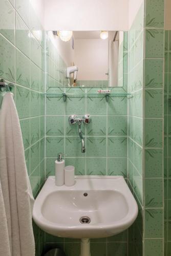 a green tiled bathroom with a sink and a mirror at Hotel JISKRA na Čeladné in Čeladná