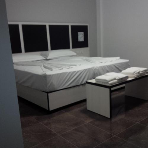 a bedroom with a large white bed and a table at Herges Hotel in Durrës