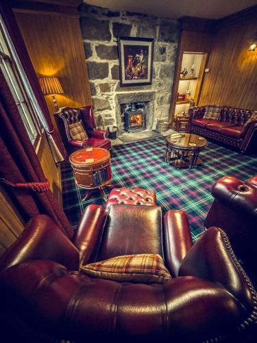 a living room with a couch and a stone fireplace at Borgie Lodge Hotel in Borgie