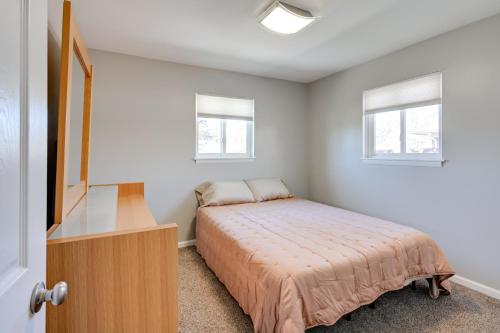 a bedroom with a bed and a dresser and two windows at 3 Mi to Dtwn Saginaw Spacious and Updated Home! in Saginaw