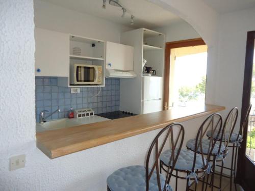 une cuisine avec deux chaises et un comptoir avec un four micro-ondes dans l'établissement Joli 2 pièces 4 personnes VUE MER, à Cavalaire-sur-Mer