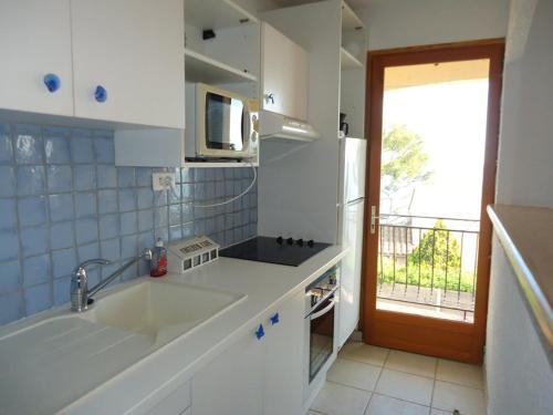 une cuisine blanche avec un évier et un micro-ondes dans l'établissement Joli 2 pièces 4 personnes VUE MER, à Cavalaire-sur-Mer
