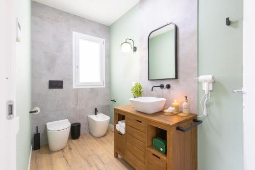 a bathroom with a sink and a toilet and a mirror at Chapelle Nove - Green Apartment in Elmas