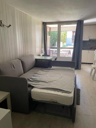 un lit dans une chambre avec un canapé et une fenêtre dans l'établissement Résidence Cybele, Studio Etage 0 proche centre du village, à Brides-les-Bains