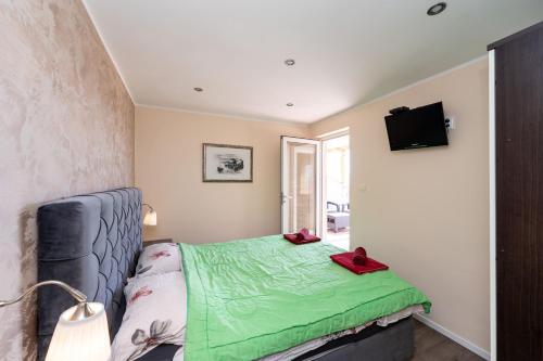 a bedroom with a bed with a green blanket at Apartments Bracic Spa in Sukošan