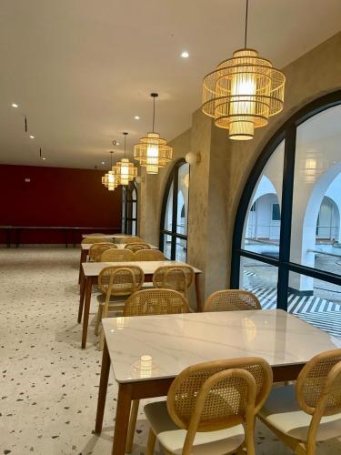 a row of tables and chairs in a room with windows at Three Oceans Resort in Kanyakumari