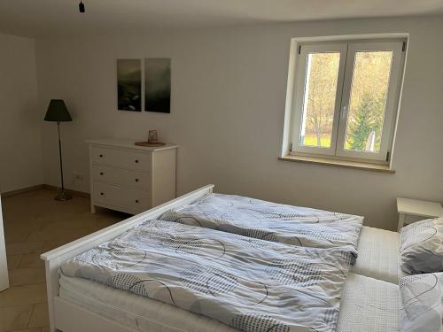 a white bedroom with a bed and a window at 2 Personen Appartement Sonnental in Greiling