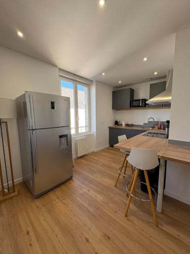 une cuisine avec un réfrigérateur en acier inoxydable et une table dans l'établissement Cozy apartment, à Plouharnel