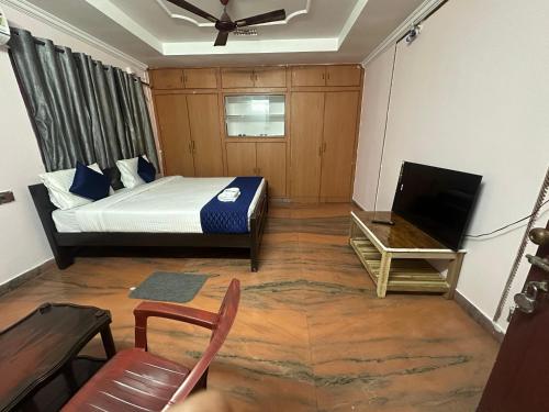 a bedroom with a bed and a tv and a chair at Hotel KP Suites Near RK Beach Vizag in Visakhapatnam
