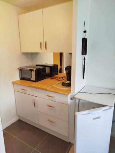 une cuisine avec des placards blancs et un four micro-ondes sur un comptoir dans l'établissement Arzon plage Fogeo terrasse kerjouanno, à Arzon