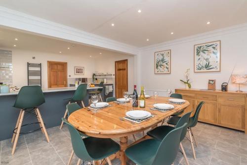 a dining room with a wooden table and green chairs at Creigia-Betws in Betws-y-coed
