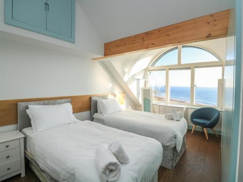 two beds in a room with a window at Hallsands Beach House in Kingsbridge