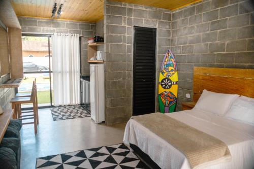 a bedroom with a bed and a surfboard on the wall at BoraMar Flats in Caraguatatuba