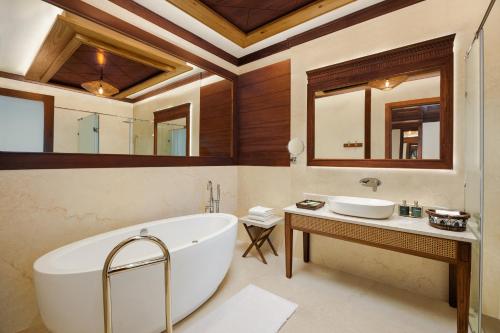 a bathroom with a large tub and a sink at Aahana Resort - Jim Corbett in Rāmnagar