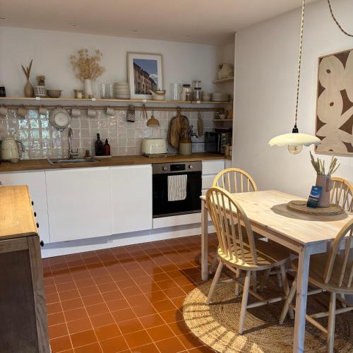 a kitchen with white cabinets and a table and chairs at Cosy, convenient flat in Falmouth in Falmouth