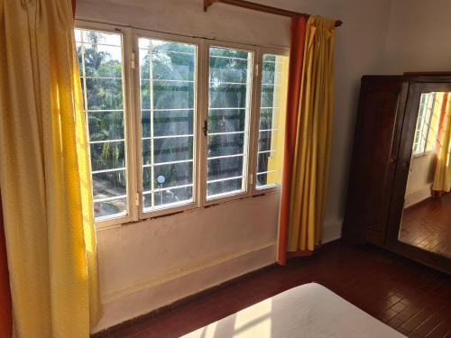 a room with two large windows with yellow curtains at Casa Al pie del Cerro in Yerba Buena
