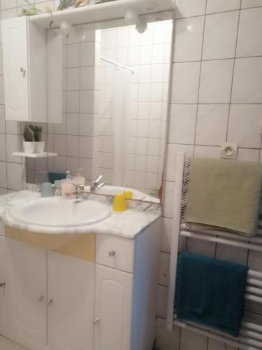 une salle de bain blanche avec un lavabo et un miroir dans l'établissement L'arbre vert Les Locations de Stéphanie, à Sondernach