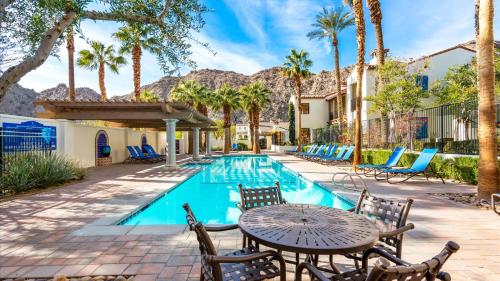 a patio with a table and chairs next to a pool at LV030 Private Upstairs Studio w Mountain Views in La Quinta
