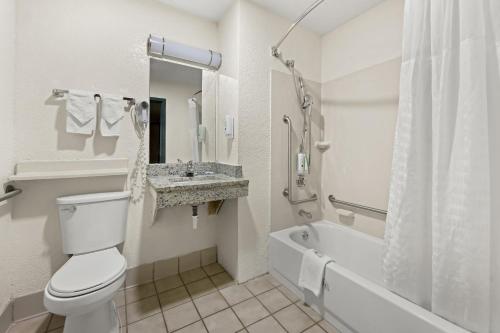 a bathroom with a toilet and a sink and a tub at Quality Inn in Rocky Mount