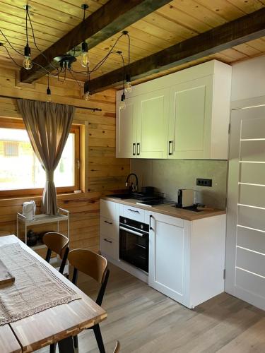 a kitchen with white cabinets and a table and a dining room at Mokrogorski konaci in Mokra Gora