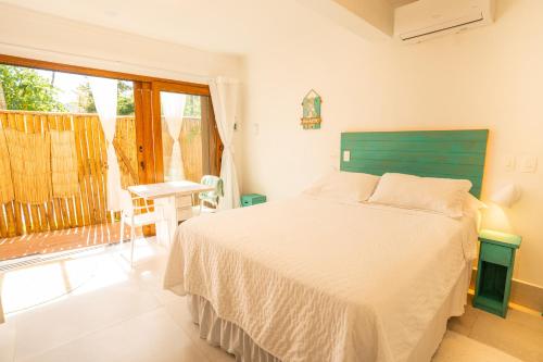 a bedroom with a bed with a green headboard and a window at Casa d'Aroeira Residencial Boutique - Centro de Juqueí - 2 quadras do mar - Serviço de Praia - Roupa de Cama 600 fios algodão Egípcio - Toalhas Banho e Praia - Tudo Novo - Estacionamento Interno - Cozinha - Consulte unidades com Ofurô Hidro e Cromoterapia in Juquei