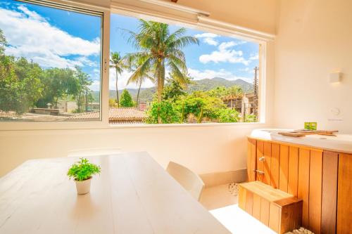 a dining room with a table and a large window at Casa d'Aroeira Residencial Boutique - Centro de Juqueí - 2 quadras do mar - Serviço de Praia - Roupa de Cama 600 fios algodão Egípcio - Toalhas Banho e Praia - Tudo Novo - Estacionamento Interno - Cozinha - Consulte unidades com Ofurô Hidro e Cromoterapia in Juquei