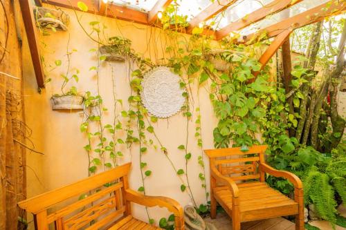 a patio with two wooden benches and plants at Casa d'Aroeira Residencial Boutique - Centro de Juqueí - 2 quadras do mar - Serviço de Praia - Roupa de Cama 600 fios algodão Egípcio - Toalhas Banho e Praia - Tudo Novo - Estacionamento Interno - Cozinha - Consulte unidades com Ofurô Hidro e Cromoterapia in Juquei