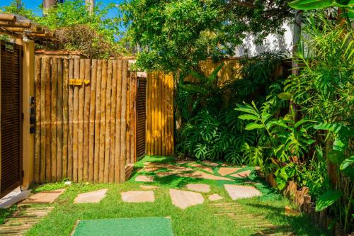 a garden with a wooden fence and a walkway at Casa d'Aroeira Residencial Boutique - Centro de Juqueí - 2 quadras do mar - Serviço de Praia - Roupa de Cama 600 fios algodão Egípcio - Toalhas Banho e Praia - Tudo Novo - Estacionamento Interno - Cozinha - Consulte unidades com Ofurô Hidro e Cromoterapia in Juquei