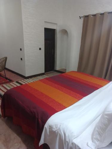 a bedroom with a bed with a rainbow blanket at kasbah Dar Bahnini in Skoura