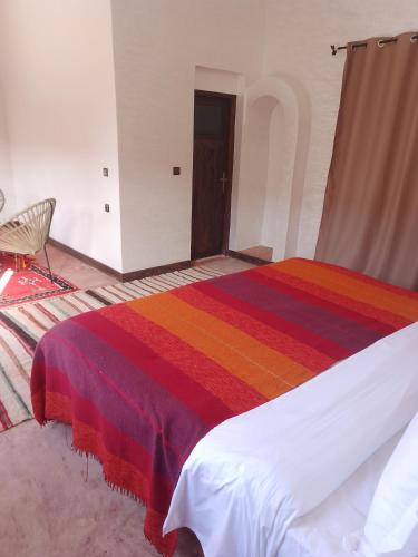a bedroom with a bed with a colorful blanket at kasbah Dar Bahnini in Skoura