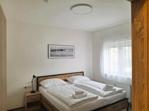 a bedroom with a bed with white sheets and a window at Apartmán Milano Frymburk in Frymburk
