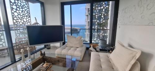 a living room with a tv and some chairs and windows at almoaj ,juman 2 marina view, in Ḩayl Āl ‘Umayr