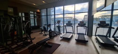 a gym with treadmills and ellipticals in a room with windows at almoaj ,juman 2 marina view, in Ḩayl Āl ‘Umayr
