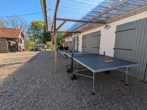 a ping pong table in a backyard with awning at Gite Valloires piscine chauffée in Rue