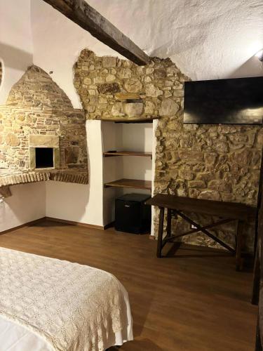 a bedroom with a stone wall with a bed and a table at Perbacco in SantʼAngelo Limosano