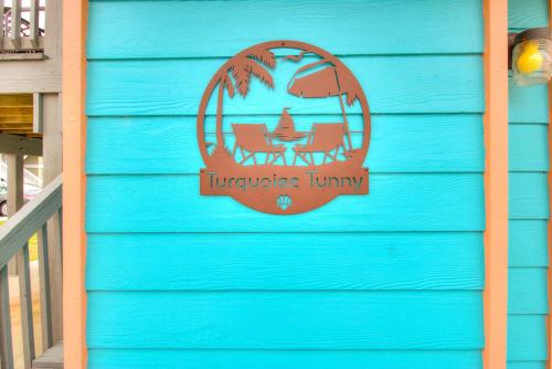 a sign on the side of a blue house at Turquoise Tunny by Carolina Beach Realty in Carolina Beach