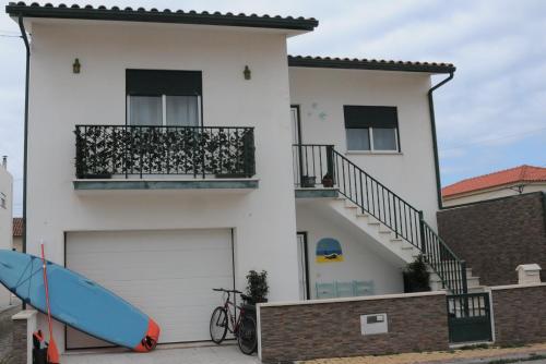 a white house with a surfboard in front of it at Casa da Costa de Lavos in Figueira da Foz