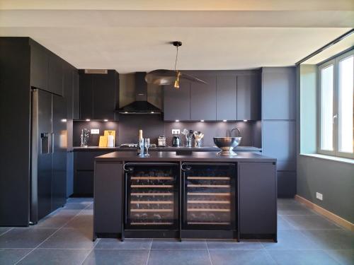 a kitchen with black cabinets and a black island at La seigneurie de Godefroy in Bouillon